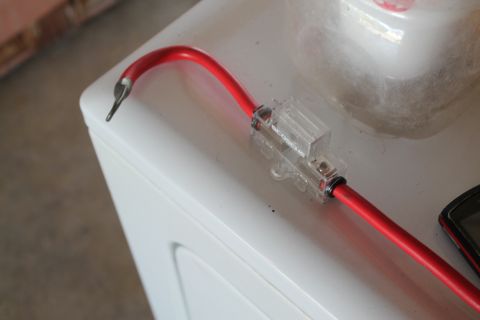 1990 Ford Bronco - Close-up of a red wire with an inline fuse holder, resting on a white surface.