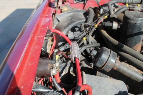 1990 Ford Bronco - Close-up view of the engine bay wiring and fuse holder on a red vehicle.
