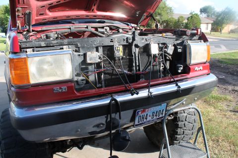 1990 Ford Bronco - Front view of a 1990 Ford Bronco with the hood up, revealing the engine compartment and wiring.