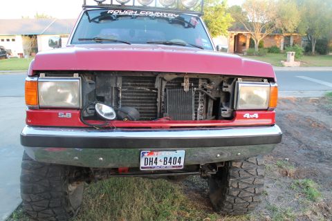 1990 Ford Bronco - This red Ford truck has its grille removed, revealing the radiator and other engine components.