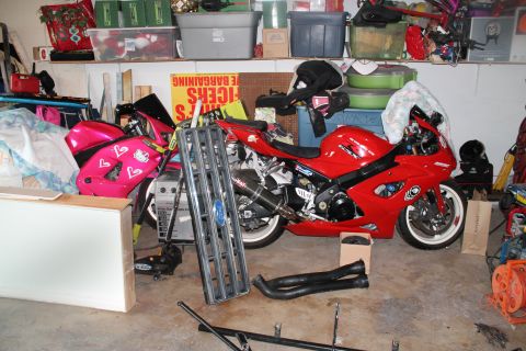 1990 Ford Bronco - Two sport motorcycles are parked in a garage filled with storage bins and miscellaneous items.