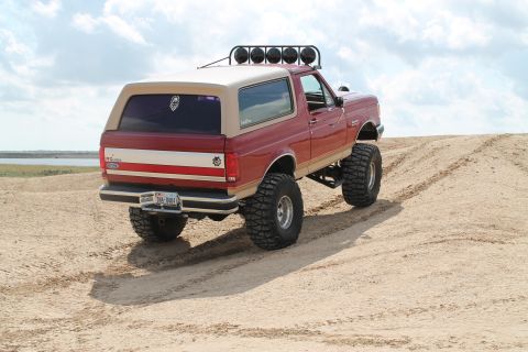 1990 Ford Bronco - This lifted 1990 Ford Bronco navigates a sandy terrain, its off-road capabilities.