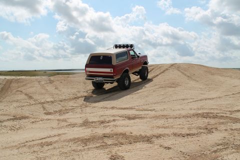 1990 Ford Bronco - This 1990 Ford Bronco is shown climbing a sand dune under a cloudy sky.