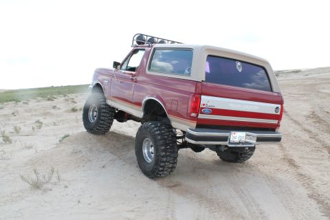 1990 Ford Bronco - This lifted 1990 Ford Bronco is shown from the rear as it navigates a sandy terrain.