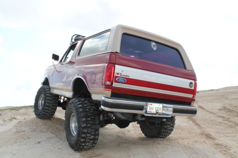 1990 Ford Bronco - Modified 1990 Ford Bronco with oversized tires and lift kit, seen from the rear.