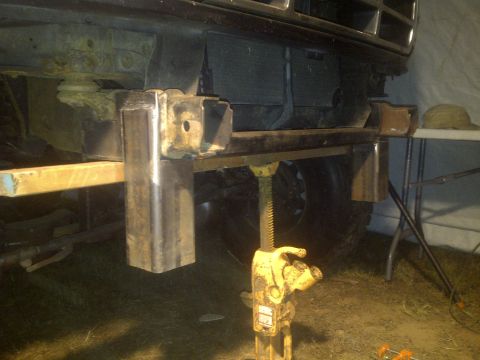 1995 Ford Bronco - Custom bumper fabrication is underway on the front of the vehicle, supported by a jack.