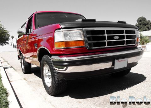 1994 Ford Bronco - The front end of a red Ford Bronco is shown parked on a street with a California license plate.