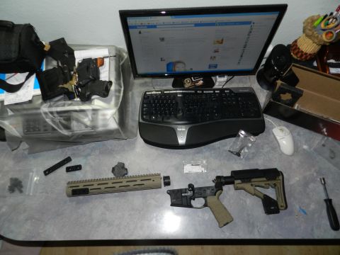 1996 Ford Bronco - A desk displays firearm components, a computer setup, and a printer, with a "SUPERMOTORS" watermark at the bottom.