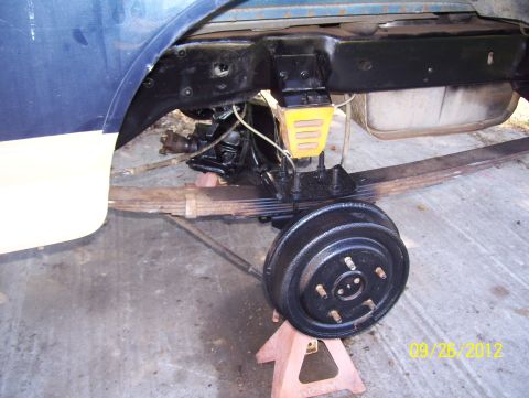 1990 Ford Bronco - Close-up view of the rear axle, drum brake, leaf springs, and fuel tank, likely during maintenance or restoration.