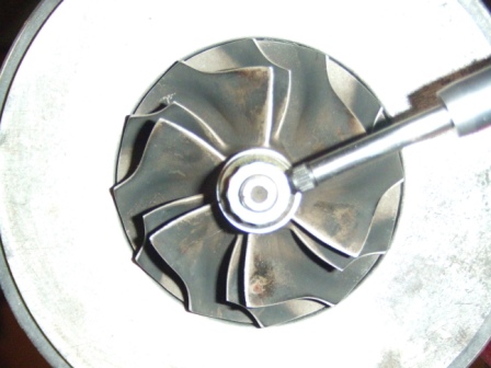 1996 Ford Bronco - A close-up view of a turbocharger compressor wheel, with a tool engaging the central nut.