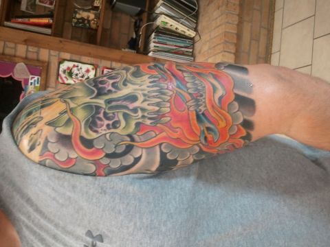 1967 Ford Mustang - A colorful tattoo a skull engulfed in flames adorns an arm, with a Supermotors.net watermark visible.