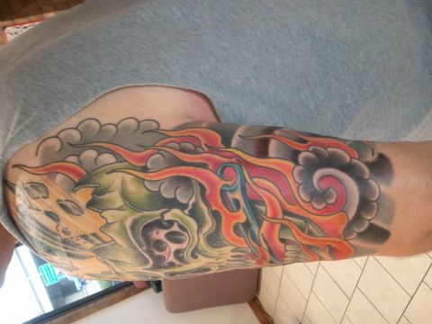 1967 Ford Mustang - This photo shows a tattoo of a skull with flames and clouds on a person's arm.