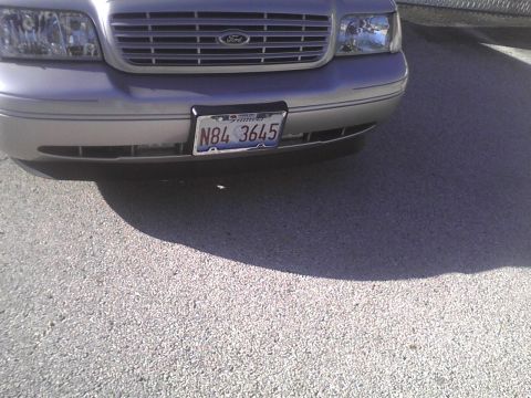 2003 Ford Crown Victoria - The front grille and headlights of a silver Ford Crown Victoria are visible, along with its license plate.
