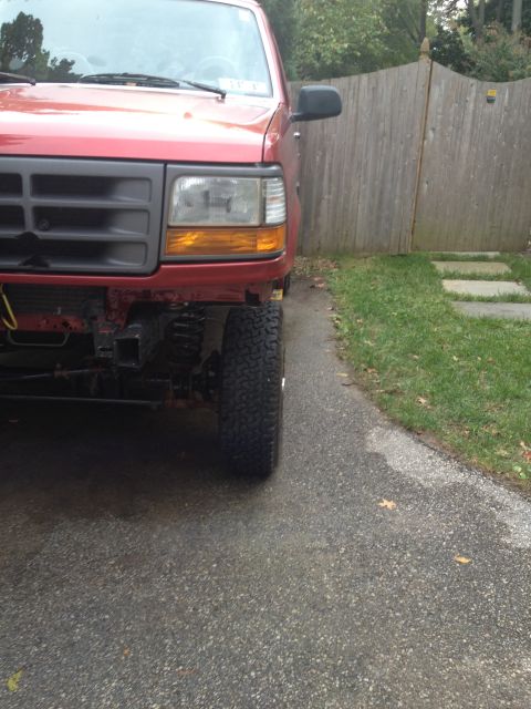 1996 Ford F-150 - Front corner view of a red 1996 Ford F-150, showing off its large tires and modified suspension.