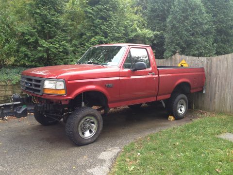 1996 Ford F-150 - A red pickup truck is parked in a driveway, with its front end slightly elevated.