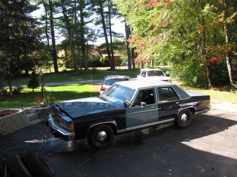 1991 Ford LTD Crown Victoria - A 1991 Ford Crown Victoria LTD with a two-tone paint job sits in a driveway with other vehicles in the background.