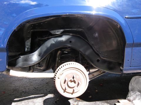 1991 Ford LTD Crown Victoria - Close-up view of the rear wheel well and suspension of a blue vehicle, highlighting the drum brake assembly and undercarriage protection.