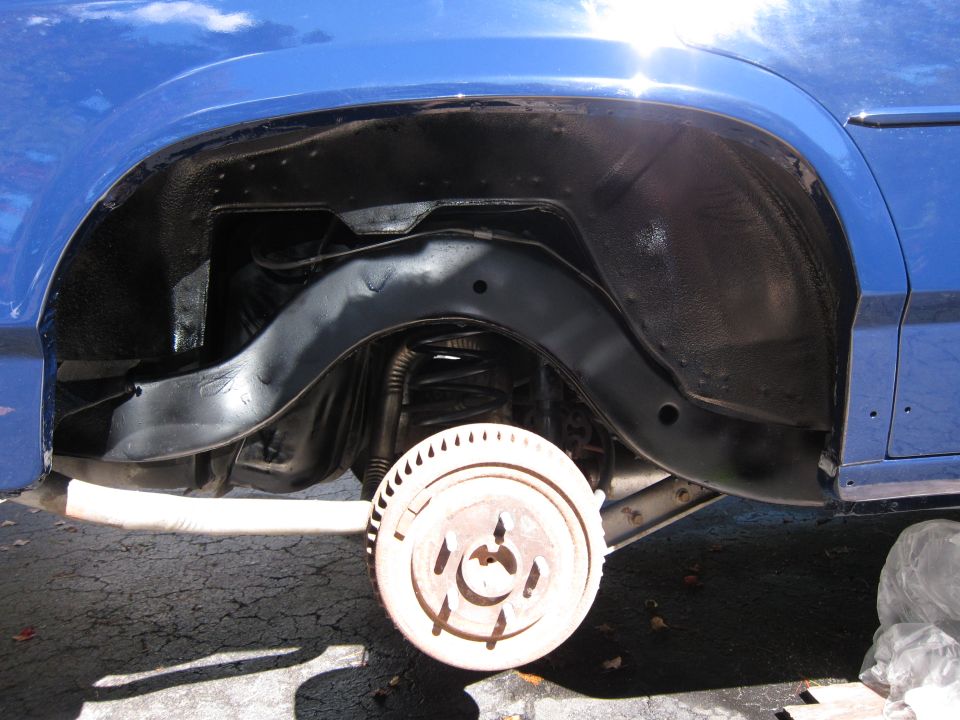 Blue car's rear wheel well and suspension components, showing drum brake