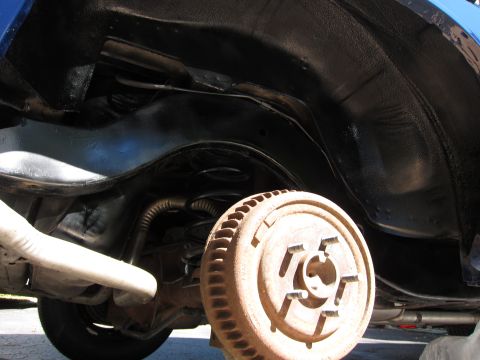1991 Ford LTD Crown Victoria - Underbody view of a vehicle, focusing on the rear suspension and brake drum assembly.