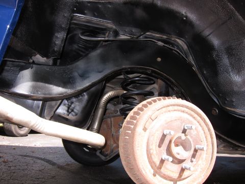1991 Ford LTD Crown Victoria - The rear suspension and brake drum of a vehicle are visible, with the brake drum showing significant rust.
