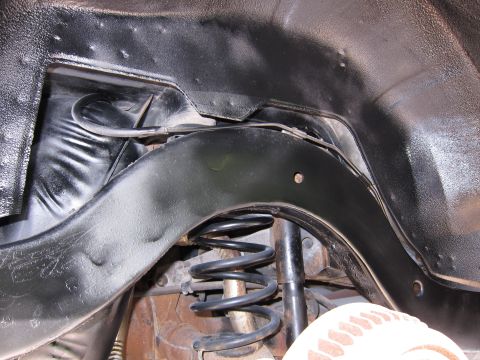 1991 Ford LTD Crown Victoria - Close-up view of the undercarriage suspension system, showing the coil spring and shock absorber.