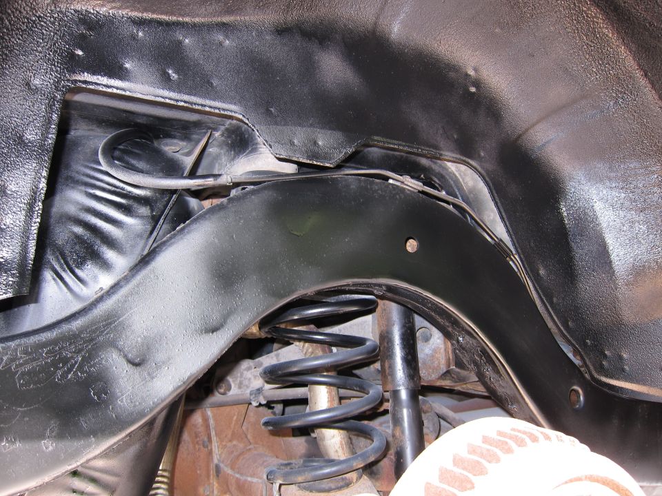 Underbody suspension with black coil spring and shock absorber, viewed from below