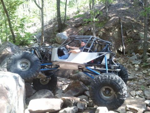 1967 Ford Mustang - A custom-built buggy with a prominent roll cage is shown tackling a challenging rocky trail.