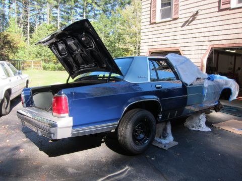 1991 Ford LTD Crown Victoria - A blue sedan is parked in a driveway with its hood and trunk open, partially covered for protection.