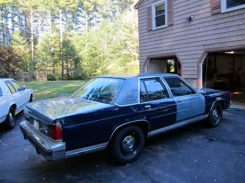1991 Ford LTD Crown Victoria - A two-tone Ford Crown Victoria is parked in front of a garage, with another car visible to the left.