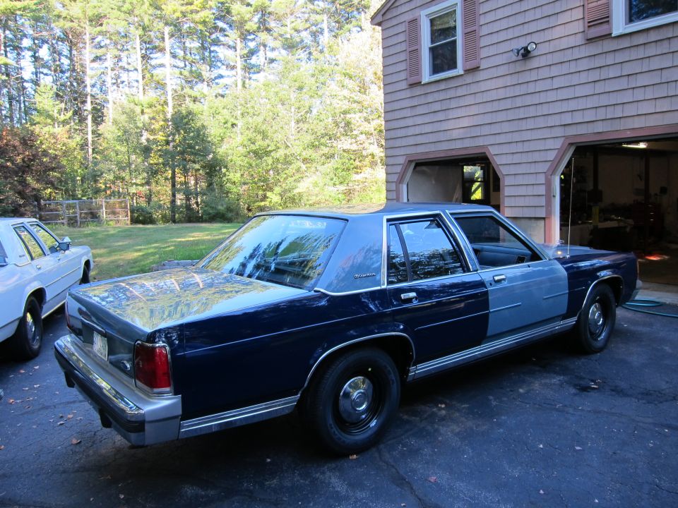 Dark blue and light blue Ford Crown Victoria parked in driveway next to a house