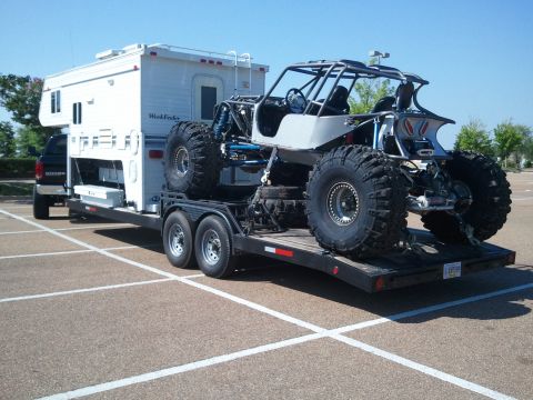 1967 Ford Mustang - A custom-built off-road buggy is transported on a trailer behind a pickup truck with a camper.