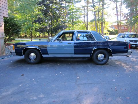 1991 Ford LTD Crown Victoria - A side view of a two-tone blue sedan, possibly a Ford Crown Victoria, parked outdoors.
