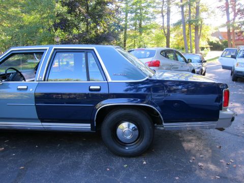 1991 Ford LTD Crown Victoria - Side view of a 1991 Ford Crown Victoria LTD, parked outdoors with other vehicles present.