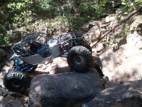 1967 Ford Mustang - A custom off-road buggy navigates a challenging rocky terrain on a wooded trail.