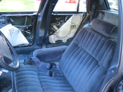 1991 Ford LTD Crown Victoria - Car interior with door panels removed, exposing wiring and insulation. Blue velour seats are present.