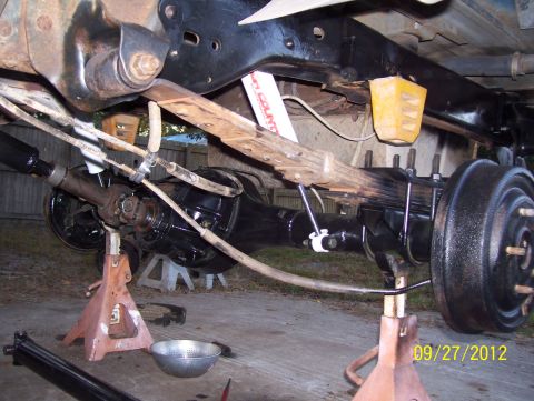 1990 Ford Bronco - Underbody view of a vehicle's rear axle and suspension system, supported by jack stands.