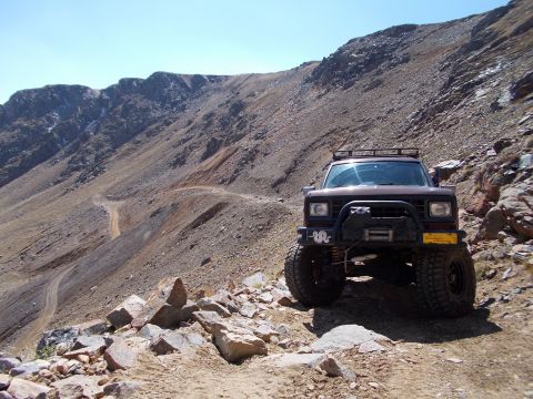 1986 Ford Bronco II - This modified SUV navigates a challenging, high-altitude dirt road with steep inclines and rocky terrain.