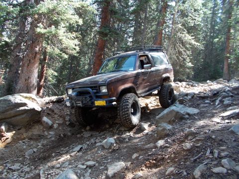 1986 Ford Bronco II - This 1986 Ford Bronco II navigates a challenging rocky path through a wooded area.