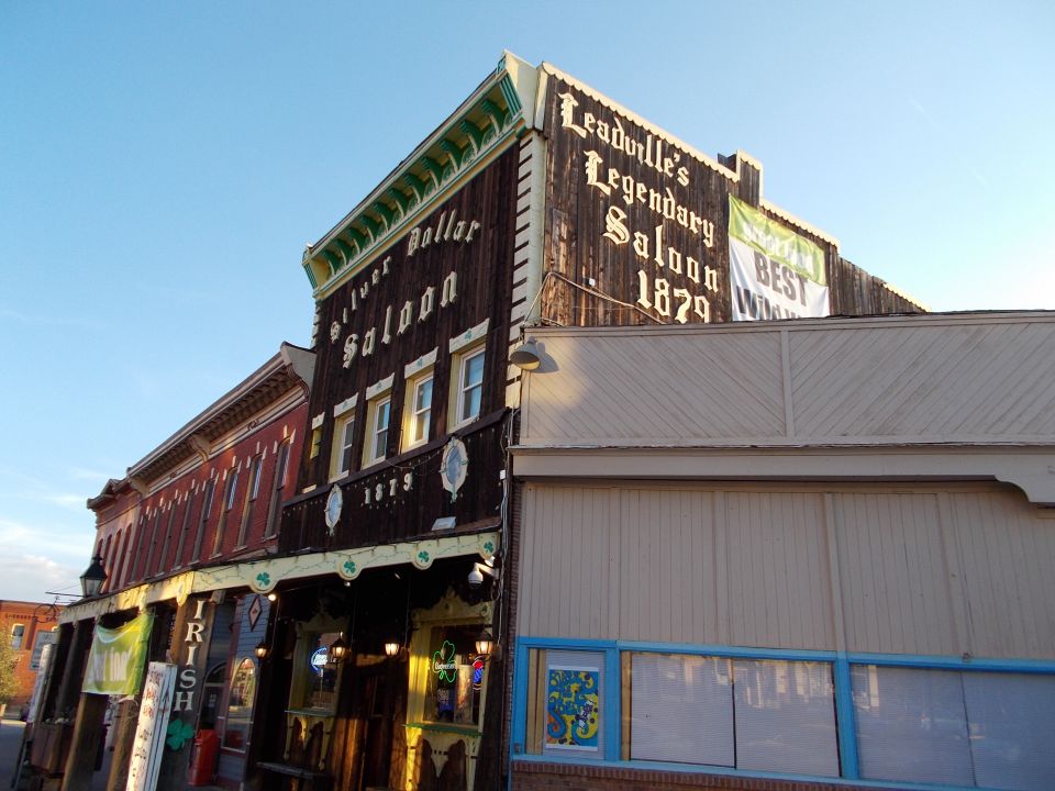 Old wooden buildings with signs for 'Silver Dollar Saloon' and 'Leadville's Legendary Saloon 1879'
