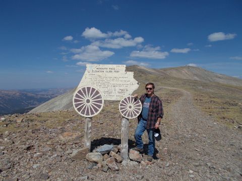 1986 Ford Bronco II - A man poses for a photo at Mosquito Pass, a high-altitude location marked by a historical sign and wagon wheel decorations.