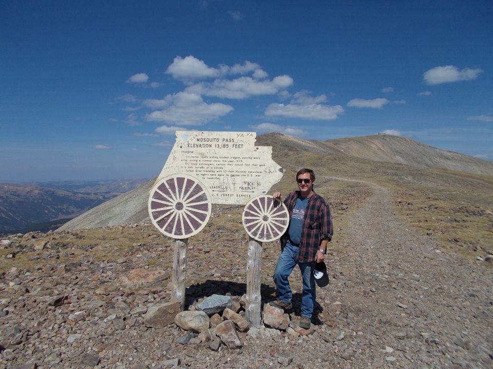 Man standing by sign at Mosquito Pass, elevation 13,185 feet