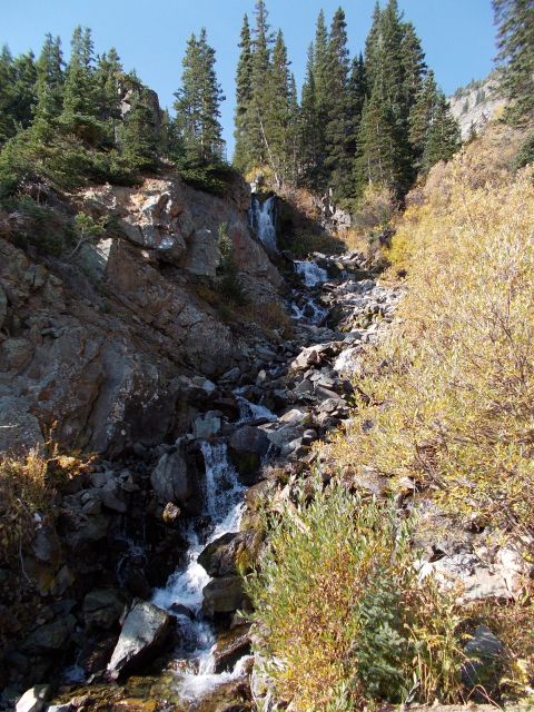 1986 Ford Bronco II - A scenic mountain landscape features a waterfall flowing over rocks, surrounded by trees and shrubs.