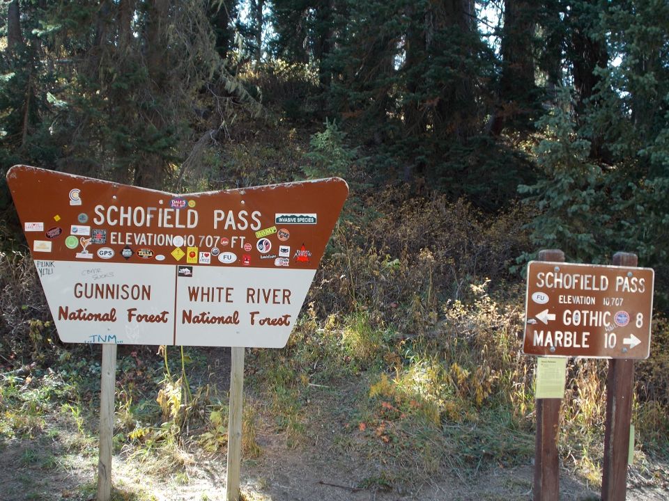 Brown and white signpost for Schofield Pass with elevation and directions to Gunnison and White River National Forests