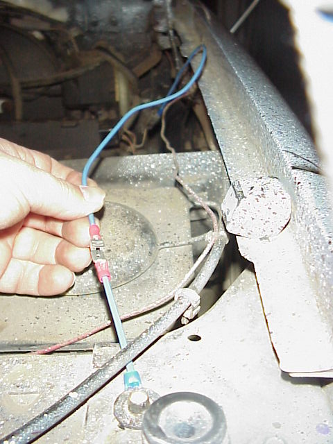 1989 Ford Bronco - A close-up shows a hand connecting a blue wire to a terminal, indicating automotive electrical maintenance or repair.