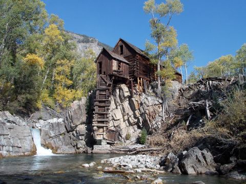 1986 Ford Bronco II - An old mill building sits precariously on a rocky cliff overlooking a river and waterfall.