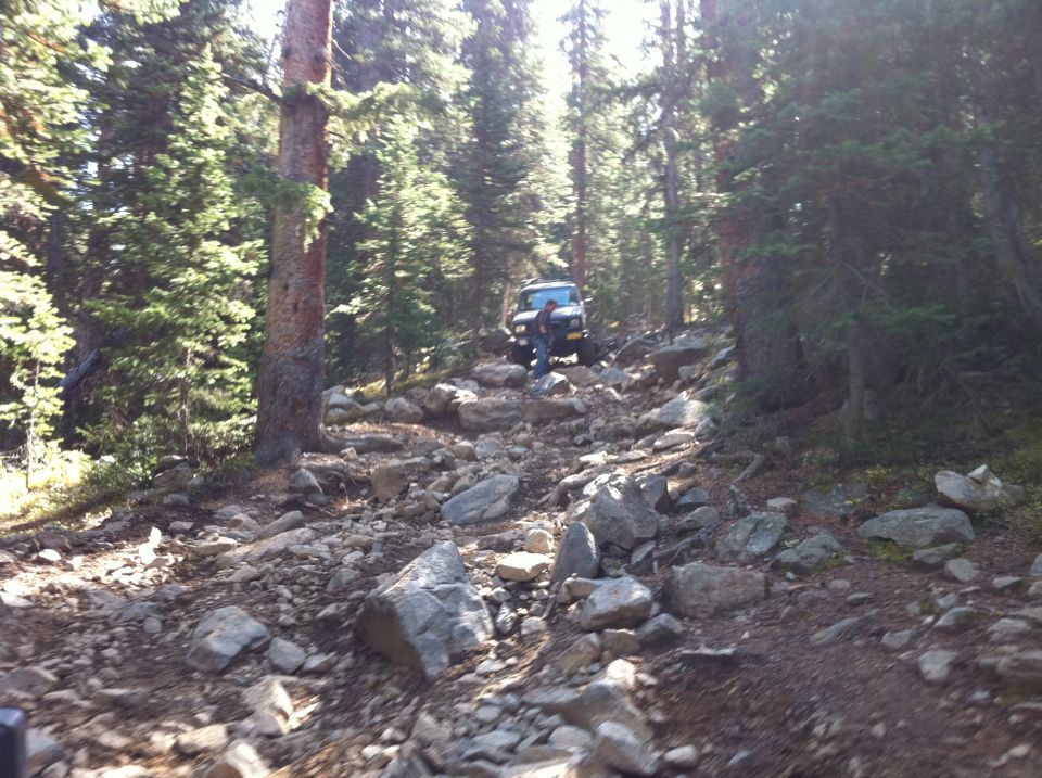 4x4 vehicle navigating a rocky, wooded trail