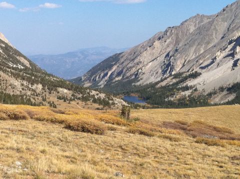 1986 Ford Bronco II - A scenic view of a mountain valley with a lake and dry grass under a blue sky.