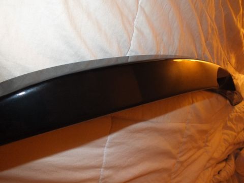 2003 Ford Crown Victoria - Curved end of a glossy black trunk spoiler shown vertically on bedding