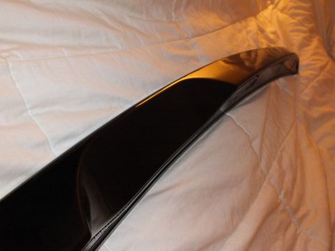 2003 Ford Crown Victoria - End detail of a black trunk lip spoiler catching warm light on a comforter