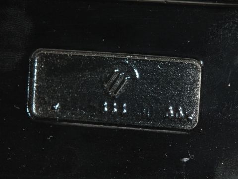 2003 Ford Crown Victoria - Macro of a stamped Mercury logo and raised dots on a glossy black component
